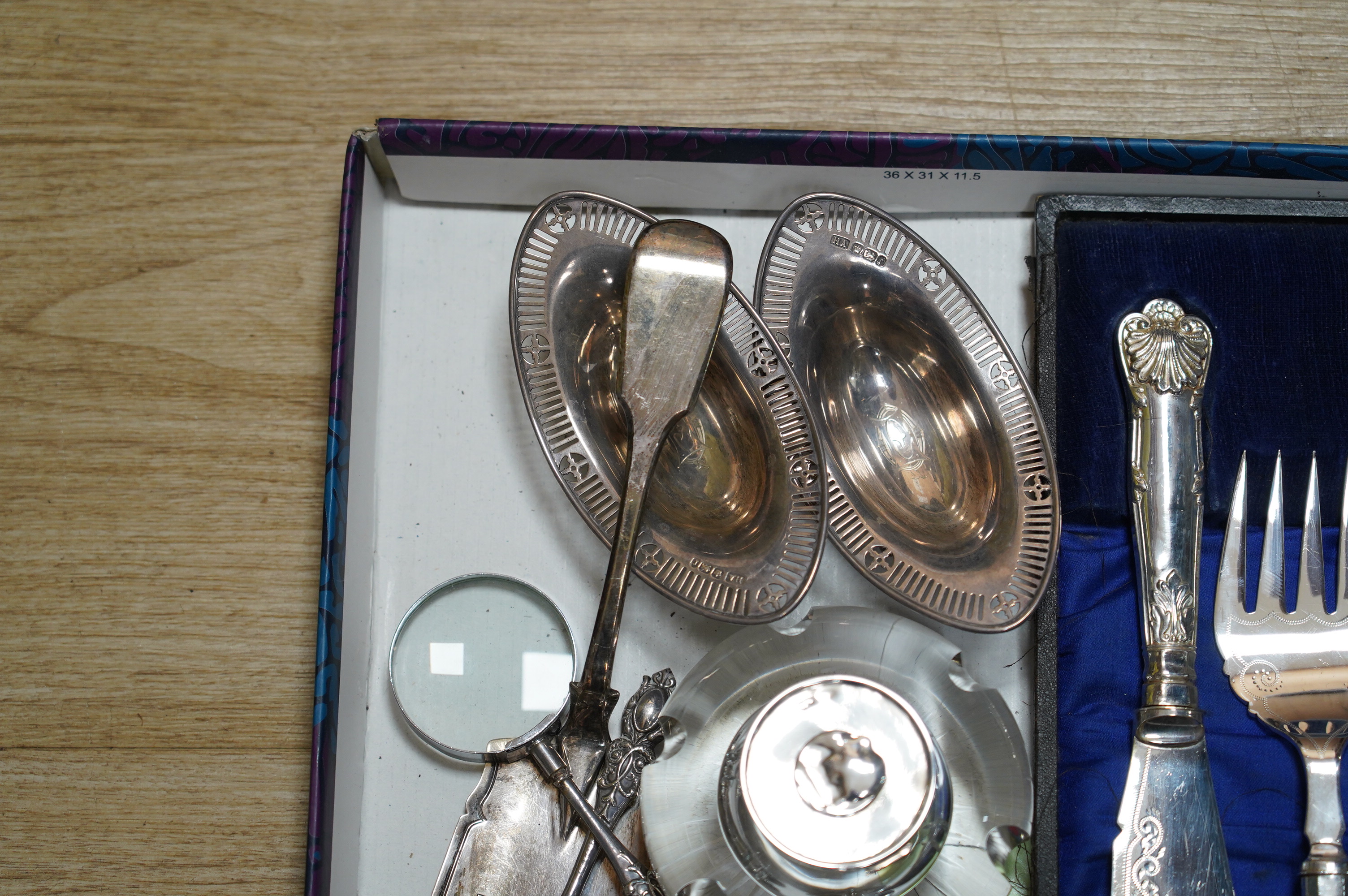 Sundry silver items including two inkwells, a William IV fiddle pattern fish slice, a pair of bonbon dishes and two handled magnifying glasses (one a.f.), together with a cased pair of plated fish servers. Condition - po